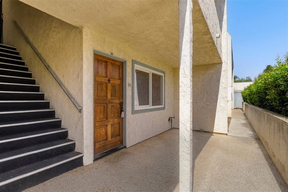 Front view of a building entrance with wooden door and staircase.