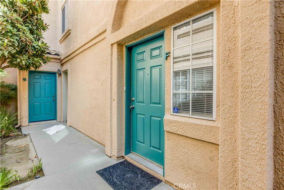 Front view of a building entrance with teal-colored doors and beige walls.