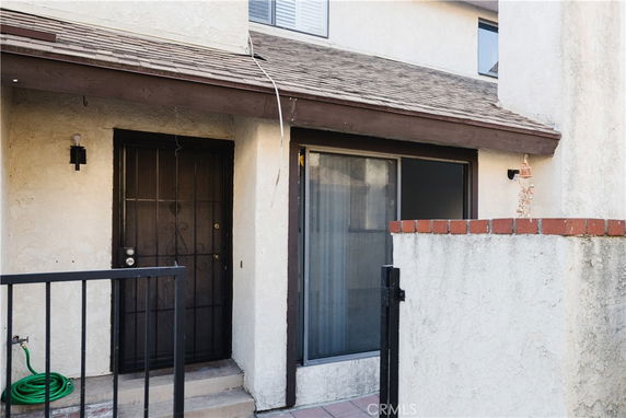 Front view of a two-story house entrance with a metal door and large window.