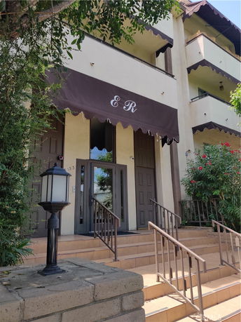 Front view of a multi-story building with a brown awning and exterior stairs.