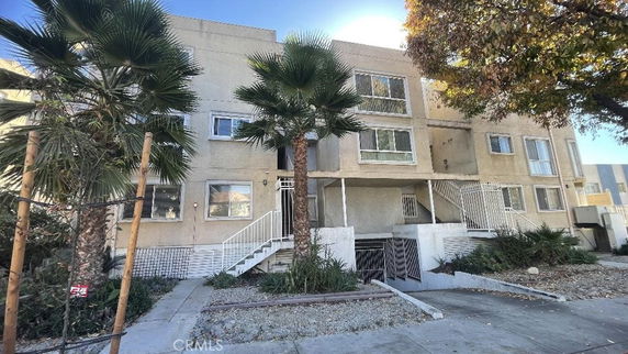 Front view of a multi-story apartment building with palm trees.