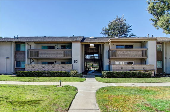 Front view of a multi-story apartment building with balconies and a central staircase.