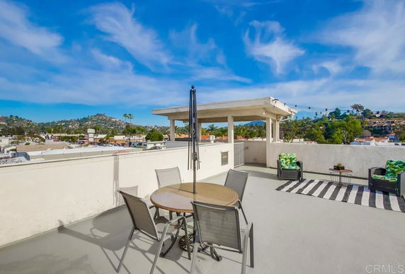 Rooftop with seating area and canopy structure, overlooking surrounding cityscape.