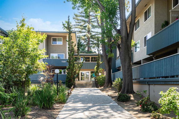 Front view of a multi-story residential building with a walkway leading to the entrance.