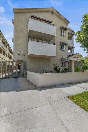 Front view of a multi-story apartment building with balconies and gated entrance.