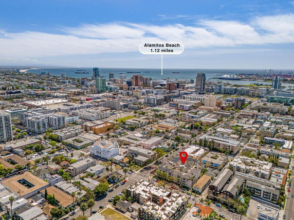 Aerial panoramic view of a city landscape with buildings and a coastline in the distance.