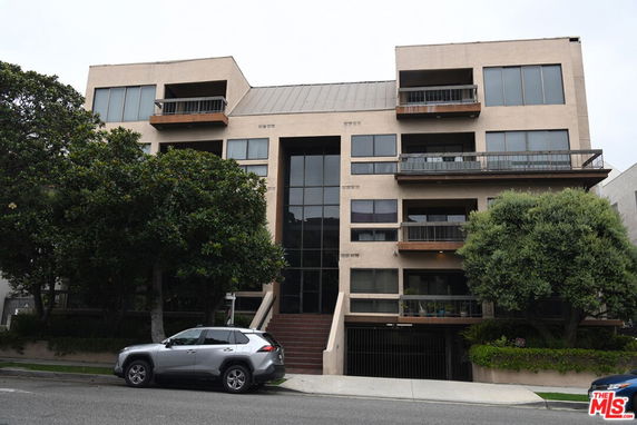 Front view of a multi-story residential building with balconies and large windows.