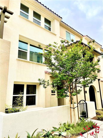 Front view of a multi-story house with multiple windows and a small gate entrance.