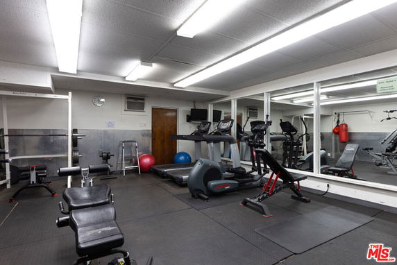 Indoor gym area with exercise equipment and mirrors on the wall