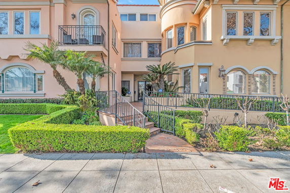 Front view of a multi-story building with balconies and landscaped garden.