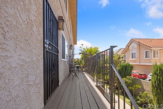 Side view of a multi-story house with a wooden deck and metal railings.