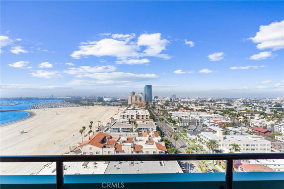 Panoramic view of a coastal cityscape with beach and tall buildings in the background.