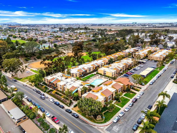 Wide aerial view of a residential complex with multiple buildings and a central swimming pool.