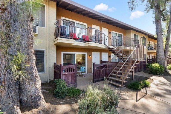 Front view of a two-story apartment building with balconies and outdoor stairs.