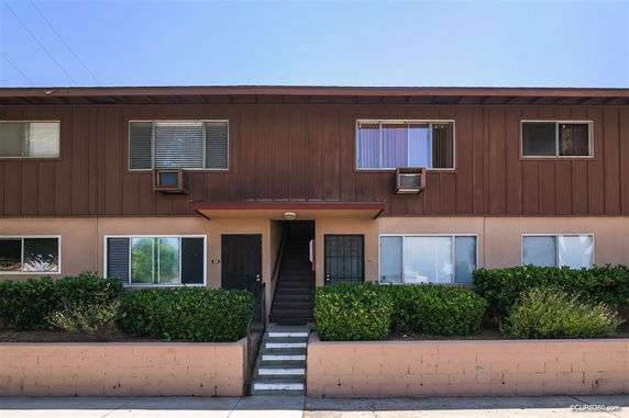 Front view of a two-story apartment building with a central staircase and multiple windows.