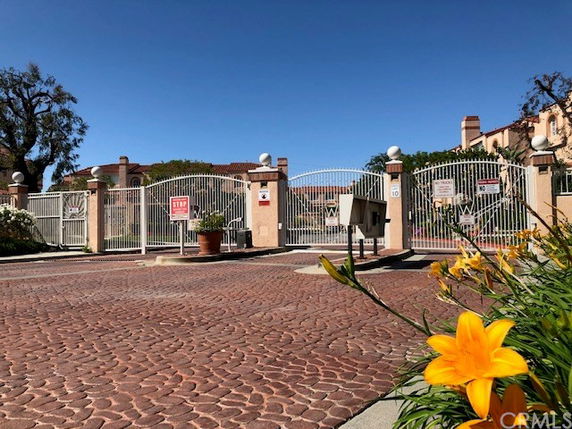 Front view of a gated entrance to a residential area with tall metal gates and drive path.