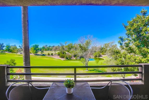 Panoramic view of a golf course from a balcony with patio furniture.