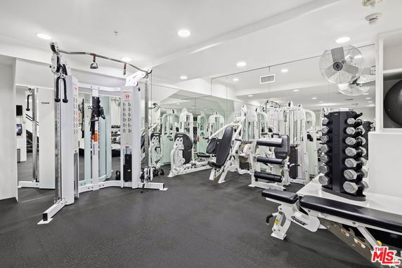 Indoor gym area with various fitness equipment and mirrors.