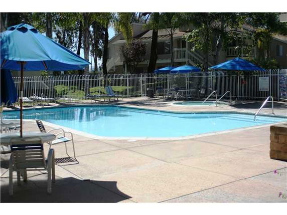 Outdoor swimming pool with lounge chairs and umbrellas.