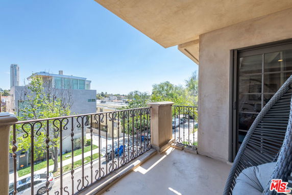 View from a balcony overlooking surrounding buildings and a clear sky.