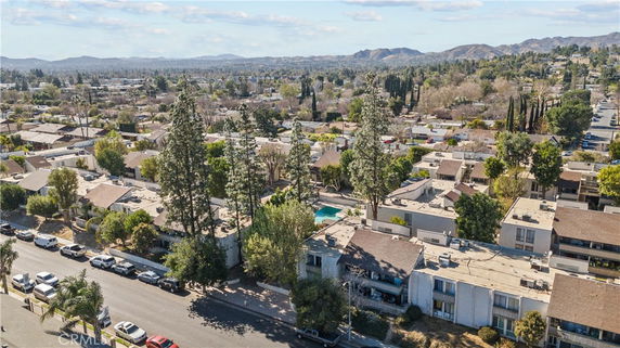 Panoramic view of a residential area with apartment buildings and houses surrounded by trees and hills.