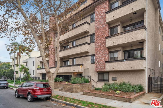 Front view of a multi-story residential building with balconies and brick facade.