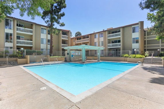 Outdoor swimming pool area in front of apartment buildings.