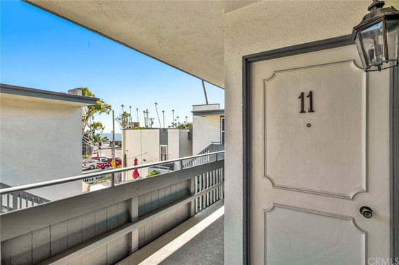 Porch area with a view of nearby buildings and distant palm trees.