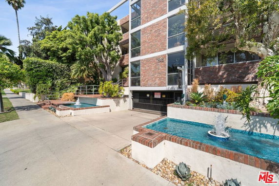 Front view of a multi-story building with brick facade and water features.