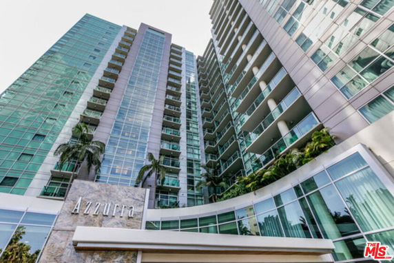 Front view of a tall modern residential building with glass facade.