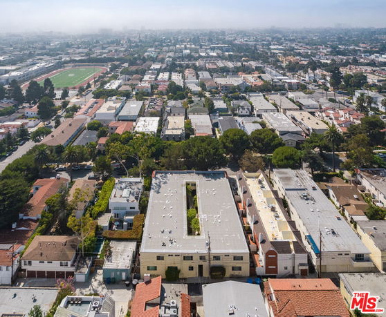 Aerial view of a residential area with buildings, streets, and a visible running track in the distance.
