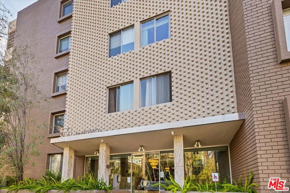 Front view of a multi-story building with a textured facade and covered entrance.