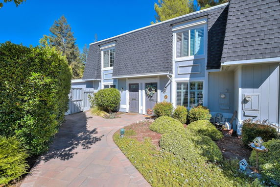 Front view of a two-story house with a sloped roof and landscaped pathway.