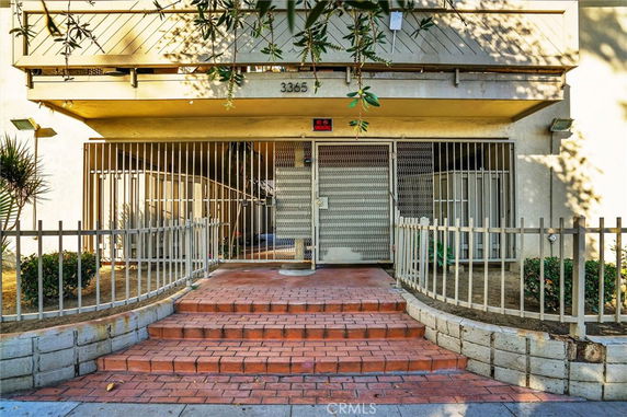 Front view of a building entrance with a gated doorway and stairs.