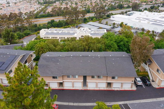 Aerial view of a residential area with multiple buildings and parking spaces, surrounded by trees.