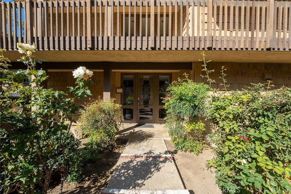 Front view of a two-story building with a wooden balcony and garden.