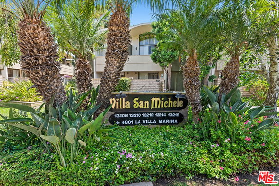 Front view of a building with palm trees and a sign reading Villa San Michele.
