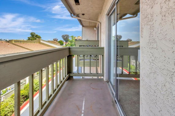 View from a balcony overlooking nearby rooftops and greenery.