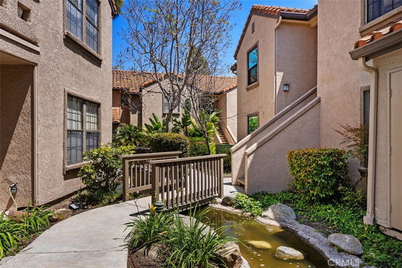 Front view of a residential building with beige stucco walls and tiled roofs.