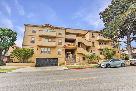 Front view of a multi-story apartment building with balconies and a garage entrance.