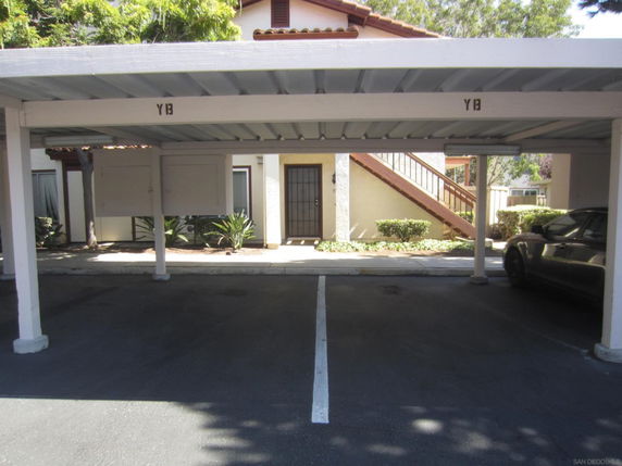 Covered parking area in front of a multi-story building.