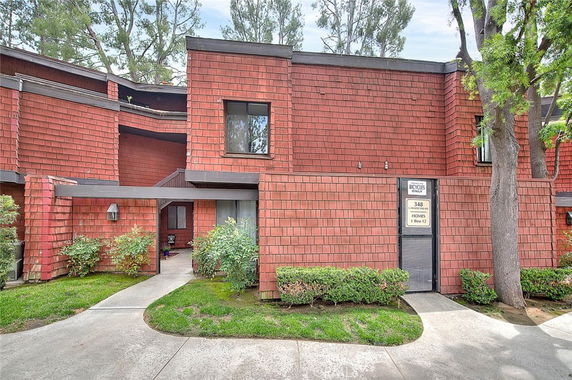 Front view of a brick townhouse with a modern design and shrubs.