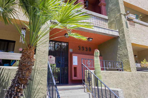 Front view of a multi-story building with a gated entrance and visible balcony.
