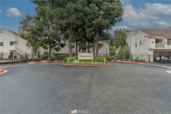 Front view of a residential building with trees and a gated entrance.