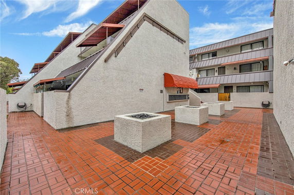 Front view of a multi-story building with triangular roofs and terracotta tiled area.