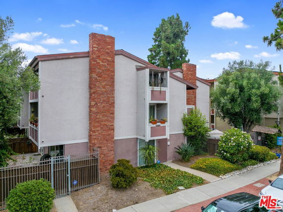 Front view of a multi-story building with brick chimneys and a gated entrance.