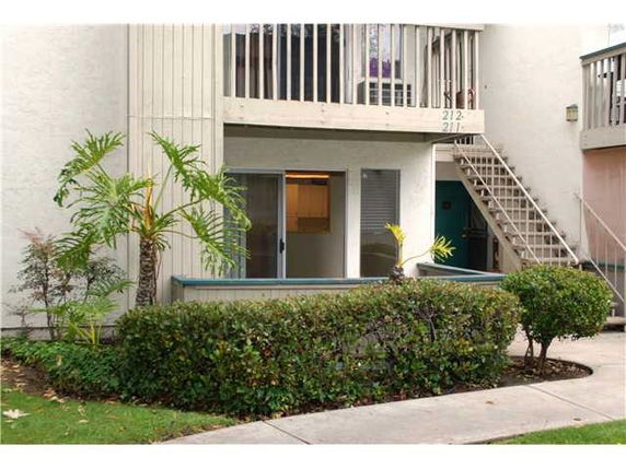 Front view of a two-story building with exterior staircase and small patio.