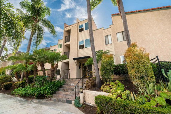 Front view of a multi-story residential building with balconies and a staircase entrance.