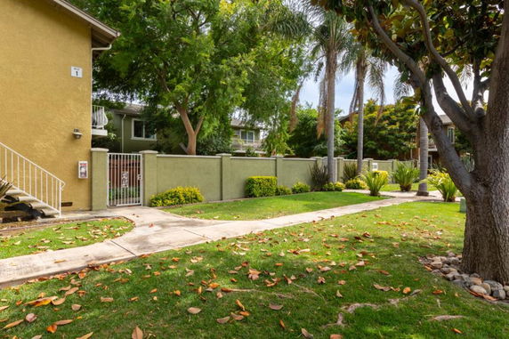 View of two-story residential building with gated entrance and surrounding trees.