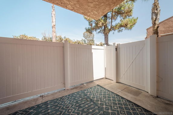 Outdoor area with a white fence and gate, partially covered by a ceiling.